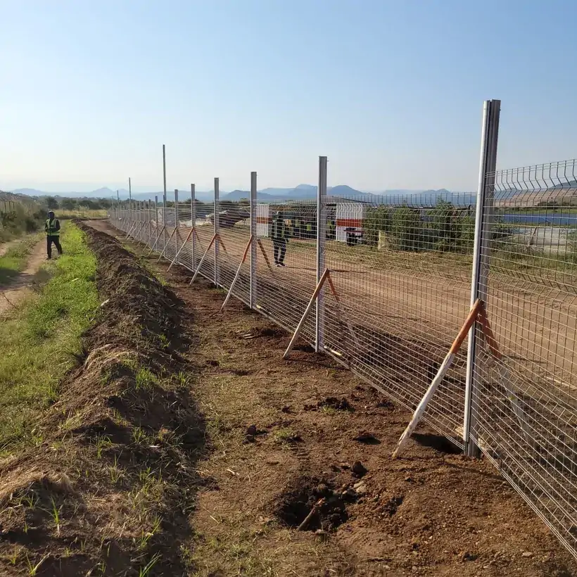 Braced fence posts and mesh beside an excavated trench during installation