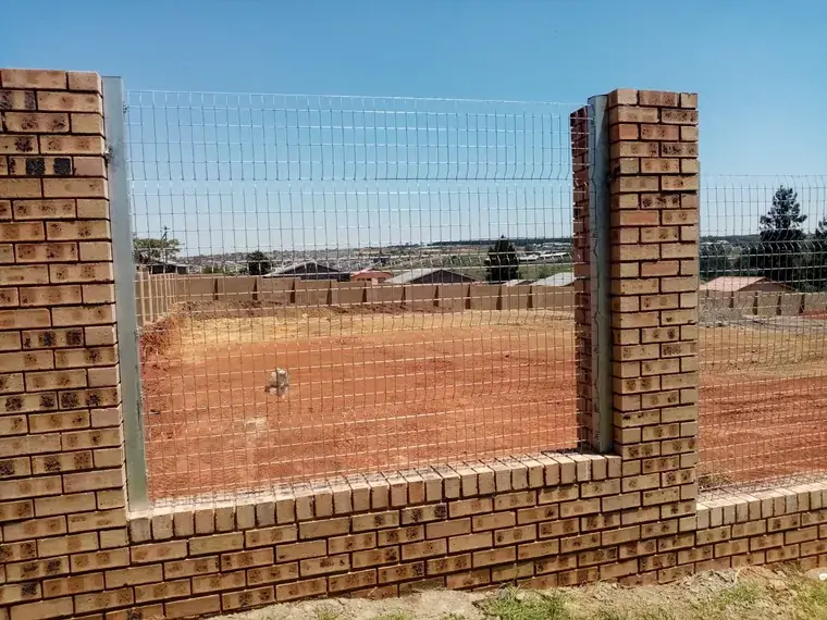 Mesh panel installed between brick pillars above a low brick wall